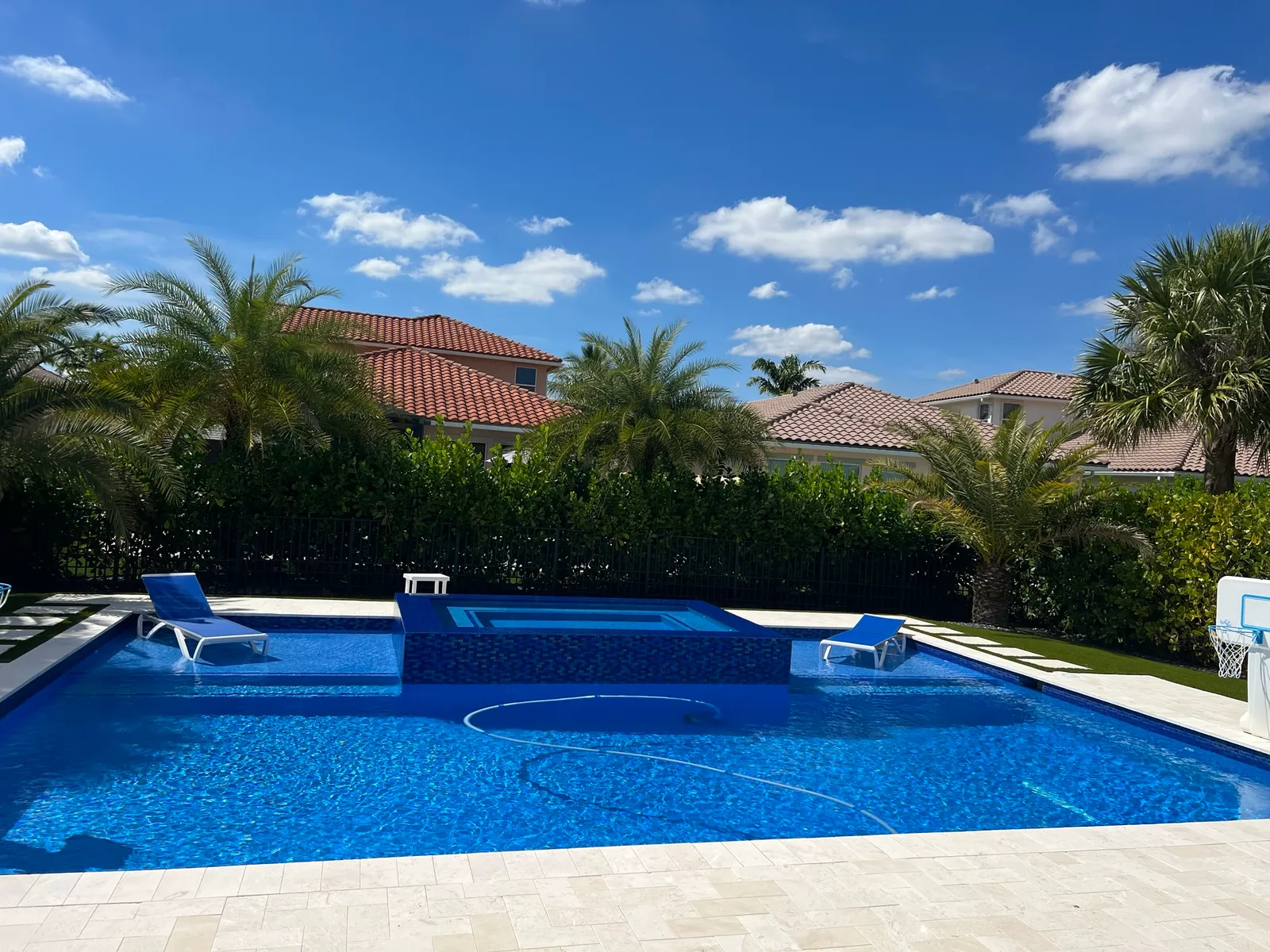New rectangular pool with raised mosaic spa, sun shelves with loungers and an ivory travertine deck.