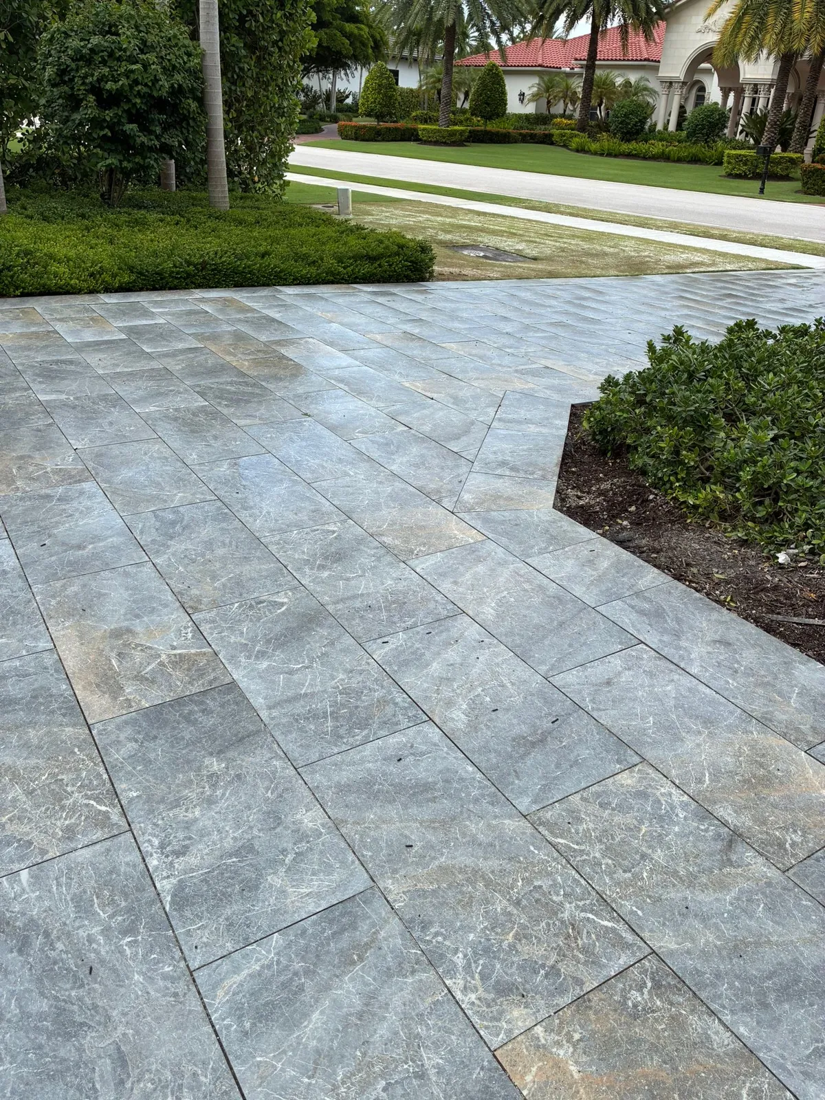 Gray marble paver driveway with a mitered edge meeting a landscaped street.