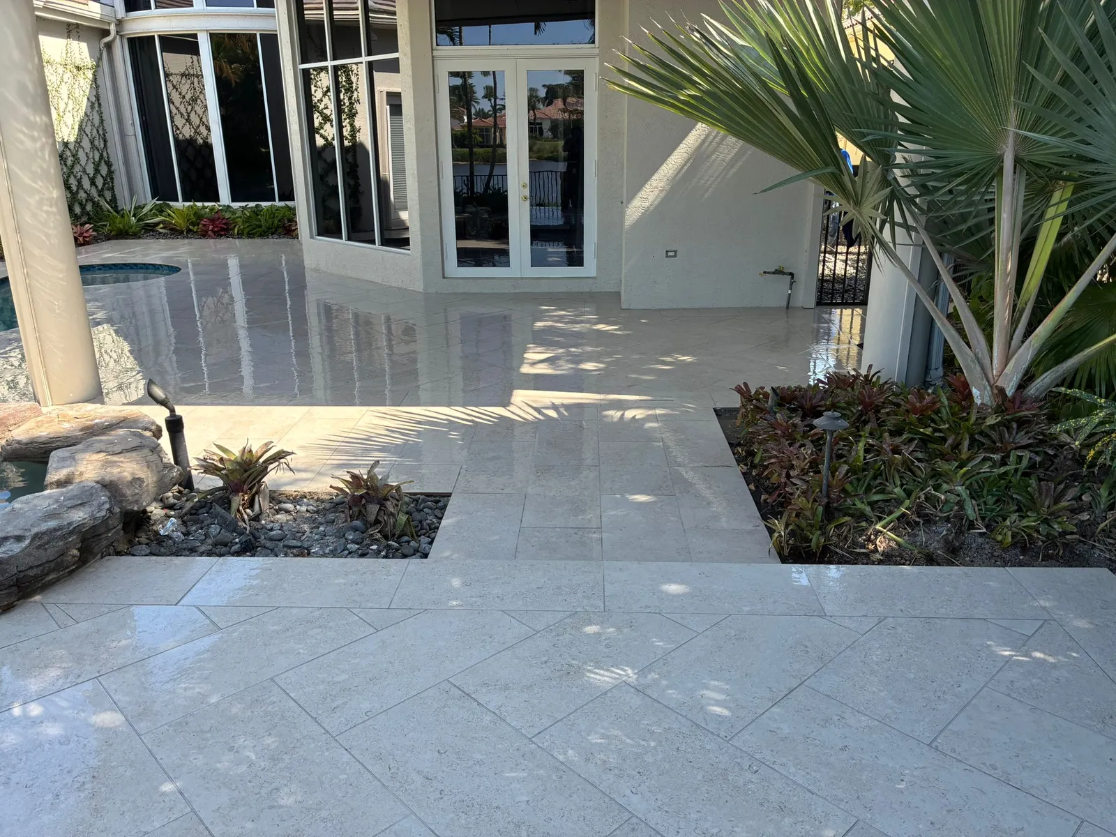 Limestone paver patio with a step down between planting beds and a fan palm.