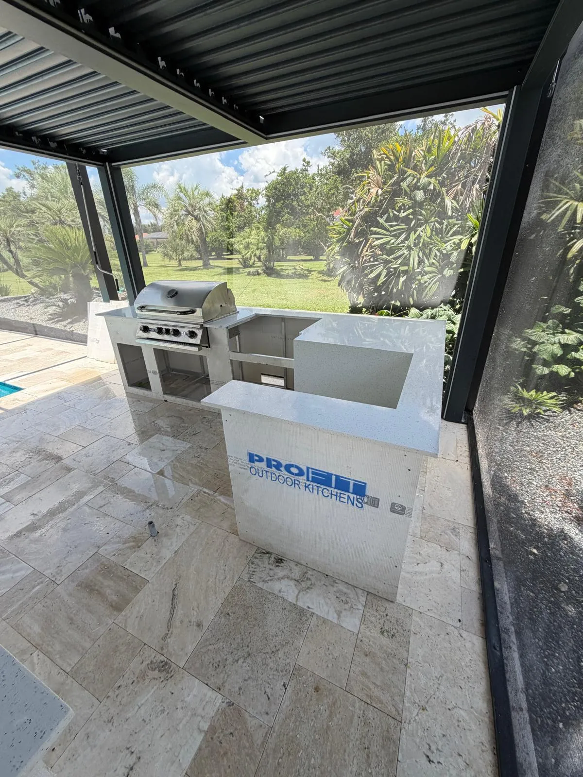 L-shaped outdoor kitchen island with built-in grill and quartz countertop in progress.