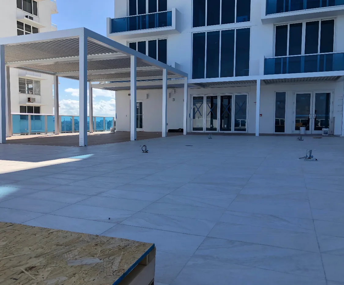 Finished white louvered pergolas at the edge of a porcelain-tiled condo rooftop.