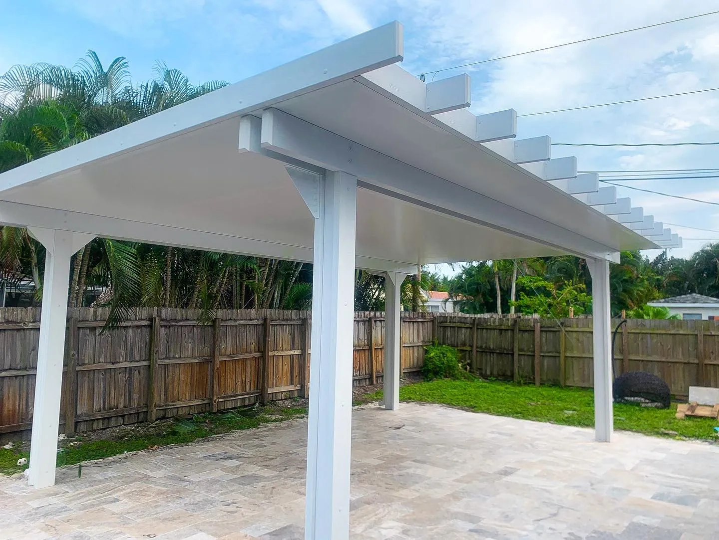 Underside of a white freestanding insulated pergola with square rafter tails over a travertine patio