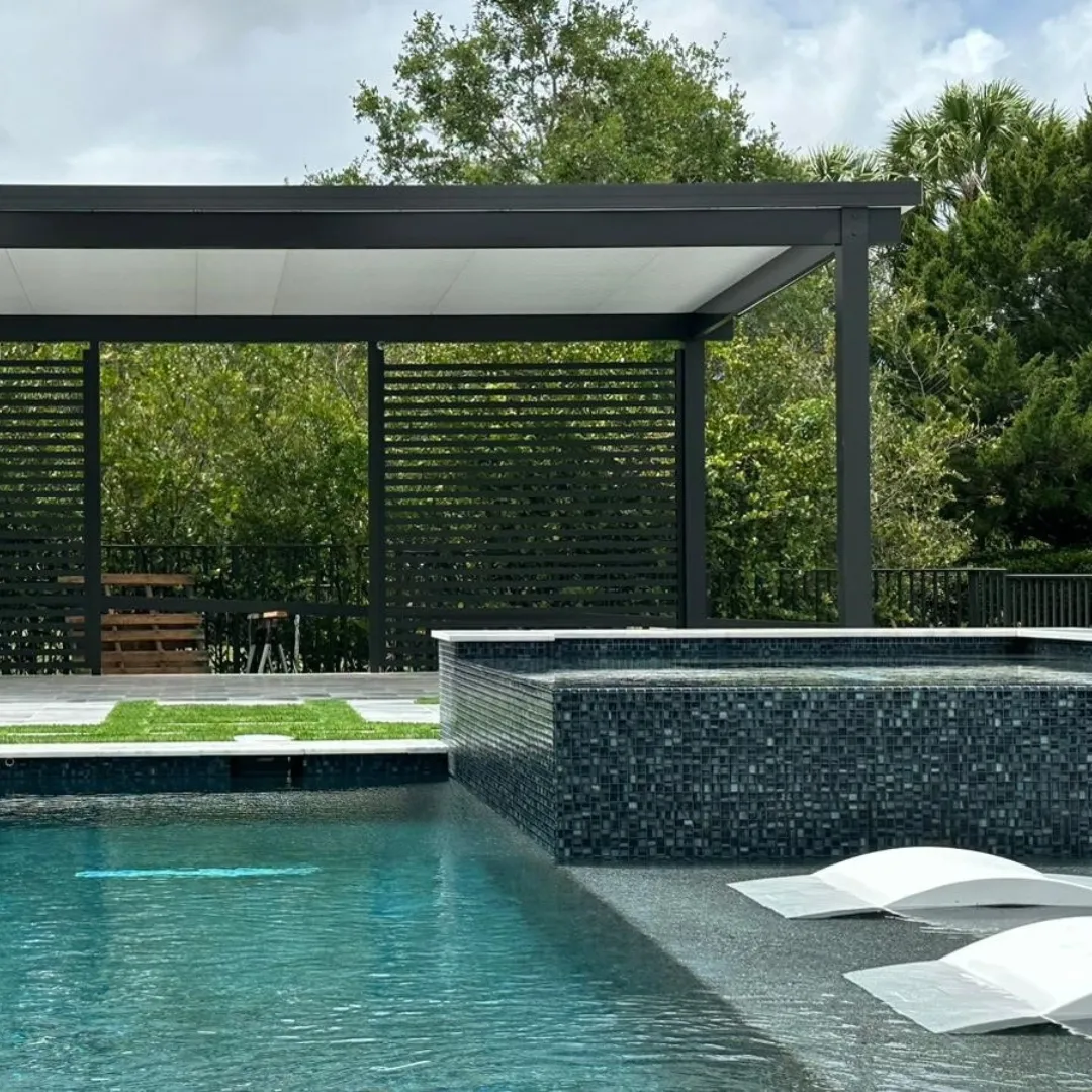 Black insulated patio cover with slat privacy walls behind a pool with dark glass tile spa.
