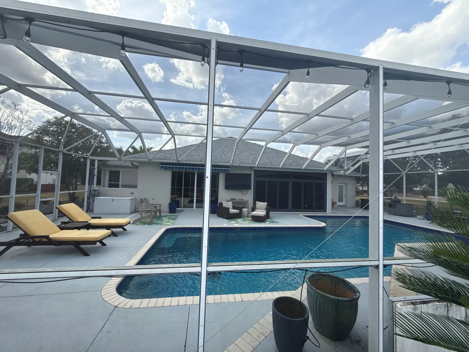 Older screened pool with painted concrete deck and brick coping before remodeling.