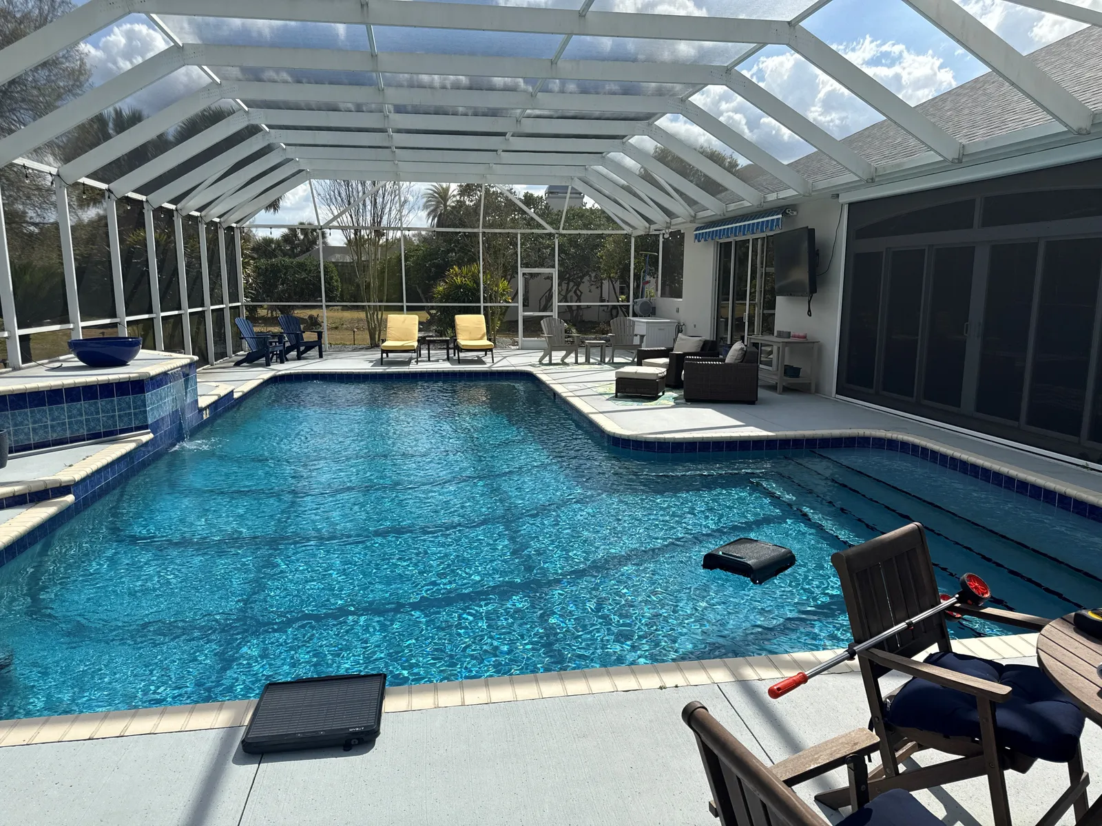 Screened pool with dated blue tile and concrete deck before a full remodel.