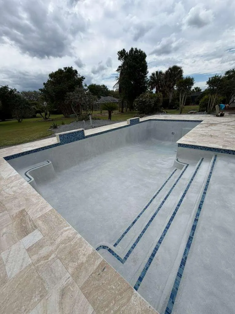 Empty pool with new plaster and steps outlined in blue mosaic tile.