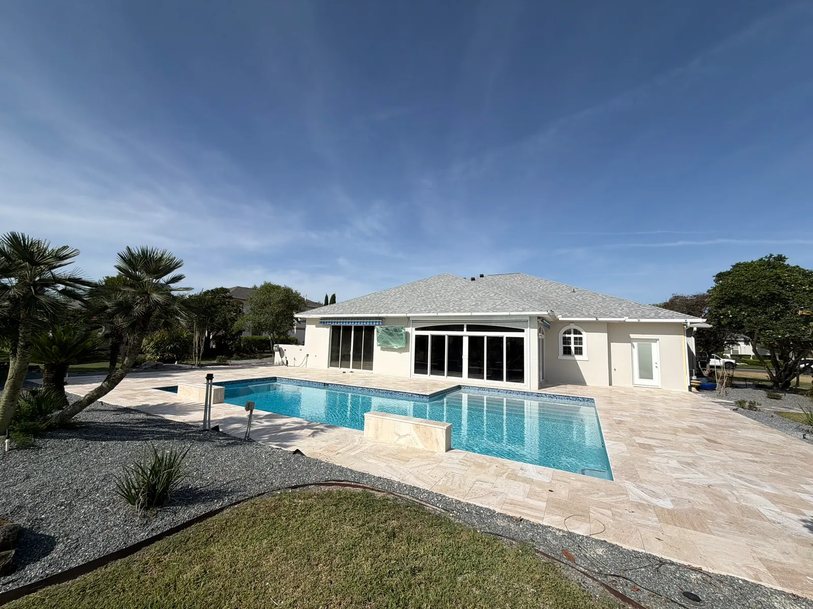 Remodeled rectangular pool with two travertine water feature walls and a large travertine deck.