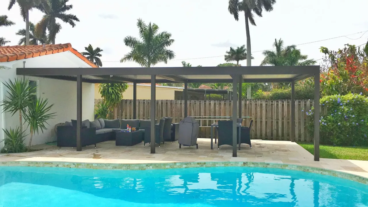 Dark bronze roof on slim posts over a sectional sofa, a covered grill and a dining set beside a freeform pool