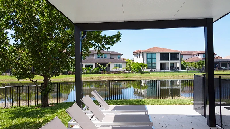Aerial view of a long lap pool alongside a covered lanai, with stepping-stone pavers across the lawn.