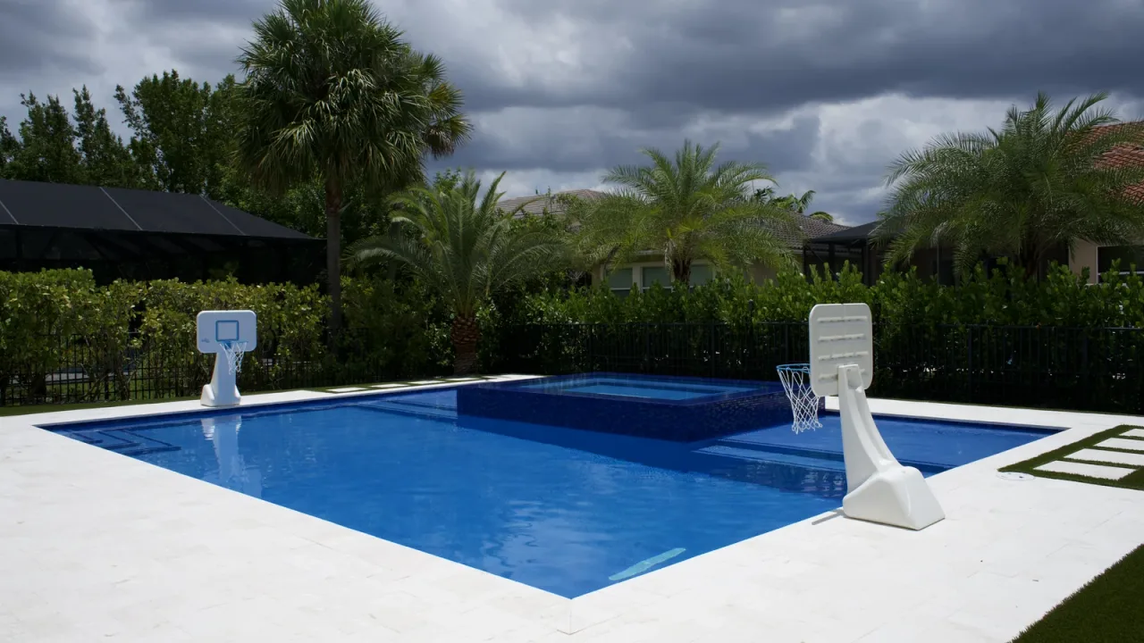 Rear of a Florida home with the remodelled pool, raised spa and stepping-stone pavers across the turf.
