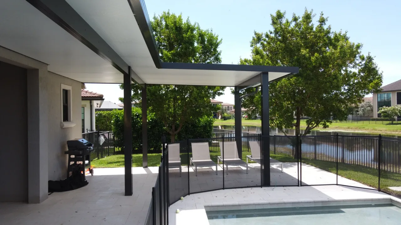 View from under an aluminium patio cover toward the lap pool and the lake behind the property.