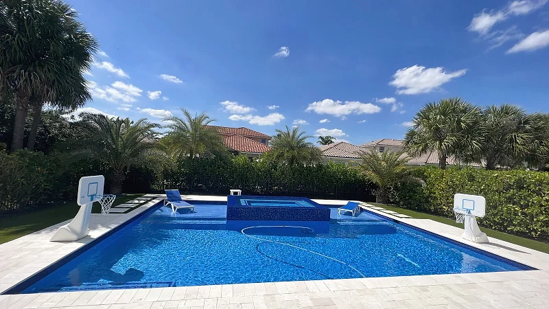 Remodelled pool with a deep-blue mosaic spa and resurfaced interior, finished with a travertine deck.
