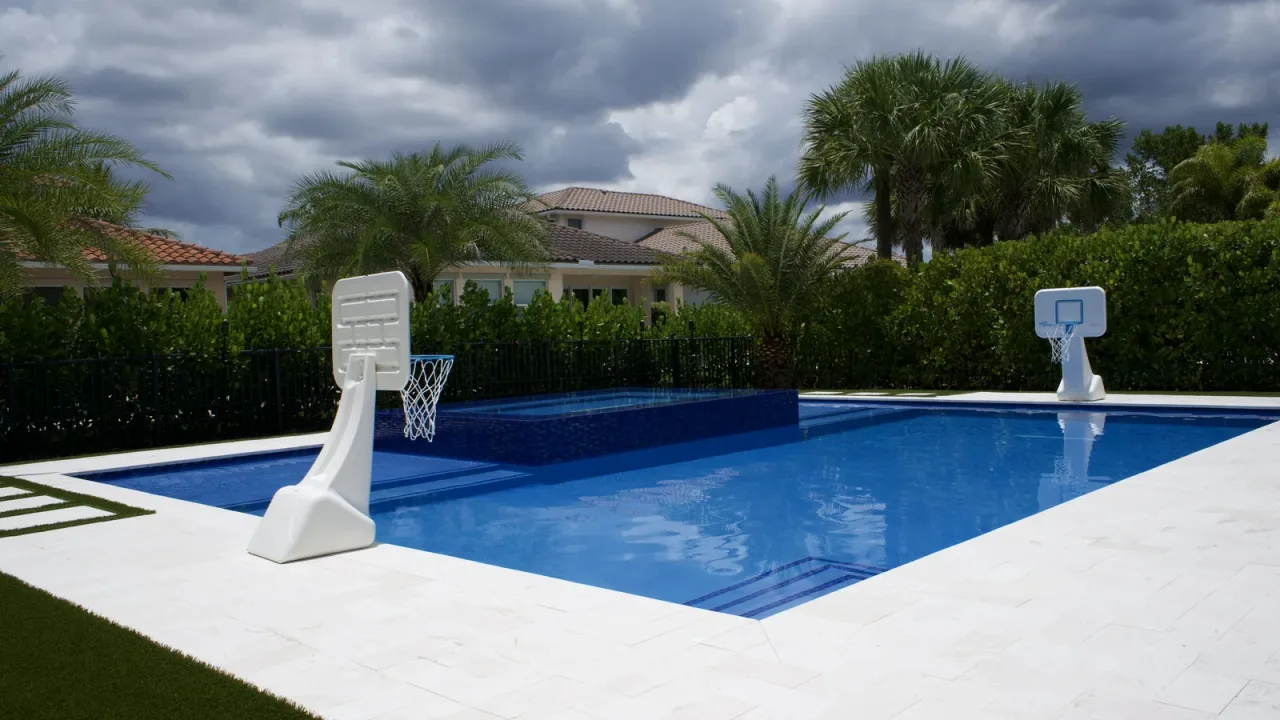 Remodelled pool and raised spa seen from the corner of the deck, with mature hedge behind.