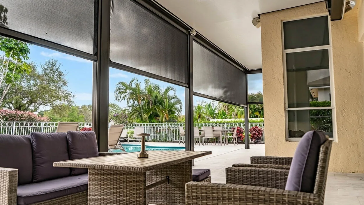 Furnished lanai behind retractable screens, with a sofa, armchairs and a dining table overlooking the pool.
