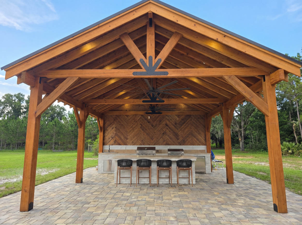 Timber pavilion installation with outdoor kitchen by Florida builders, combining pergola structure and entertainment space.