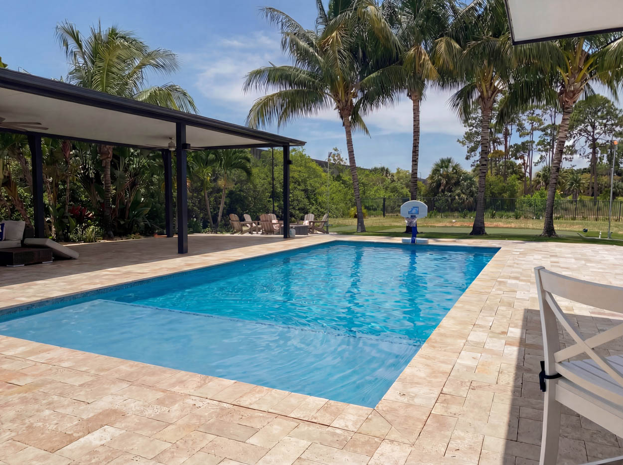 High-end residential pool with covered patio and outdoor kitchen, installed by professional pool contractors in Florida.