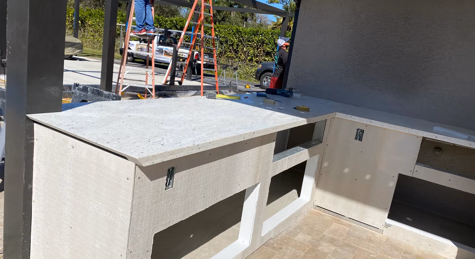 L-shaped outdoor kitchen base in cement board with new stone countertop set in place.