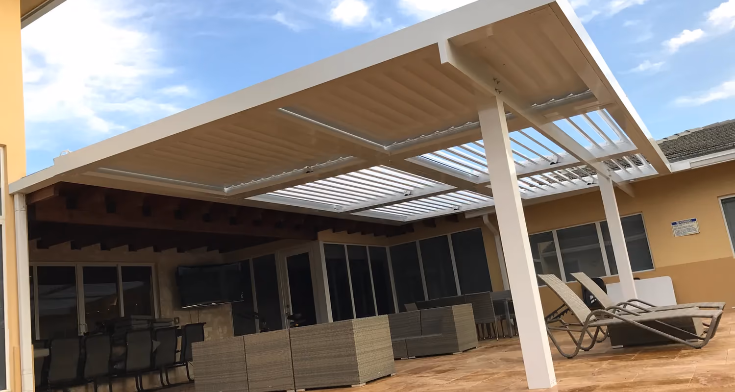 Large white louvered roof with partly open blades over a travertine patio with wicker lounge furniture