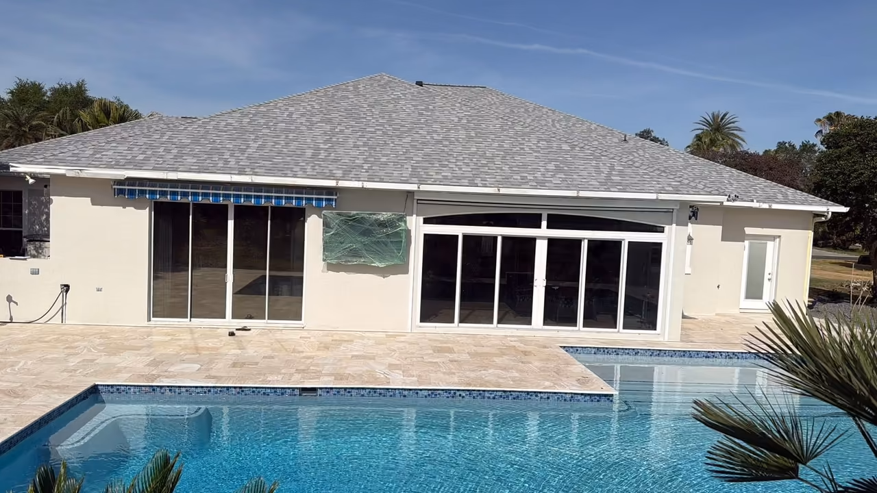 After: the same pool with blue glass waterline tile and an ivory travertine deck, pool renovation in Florida