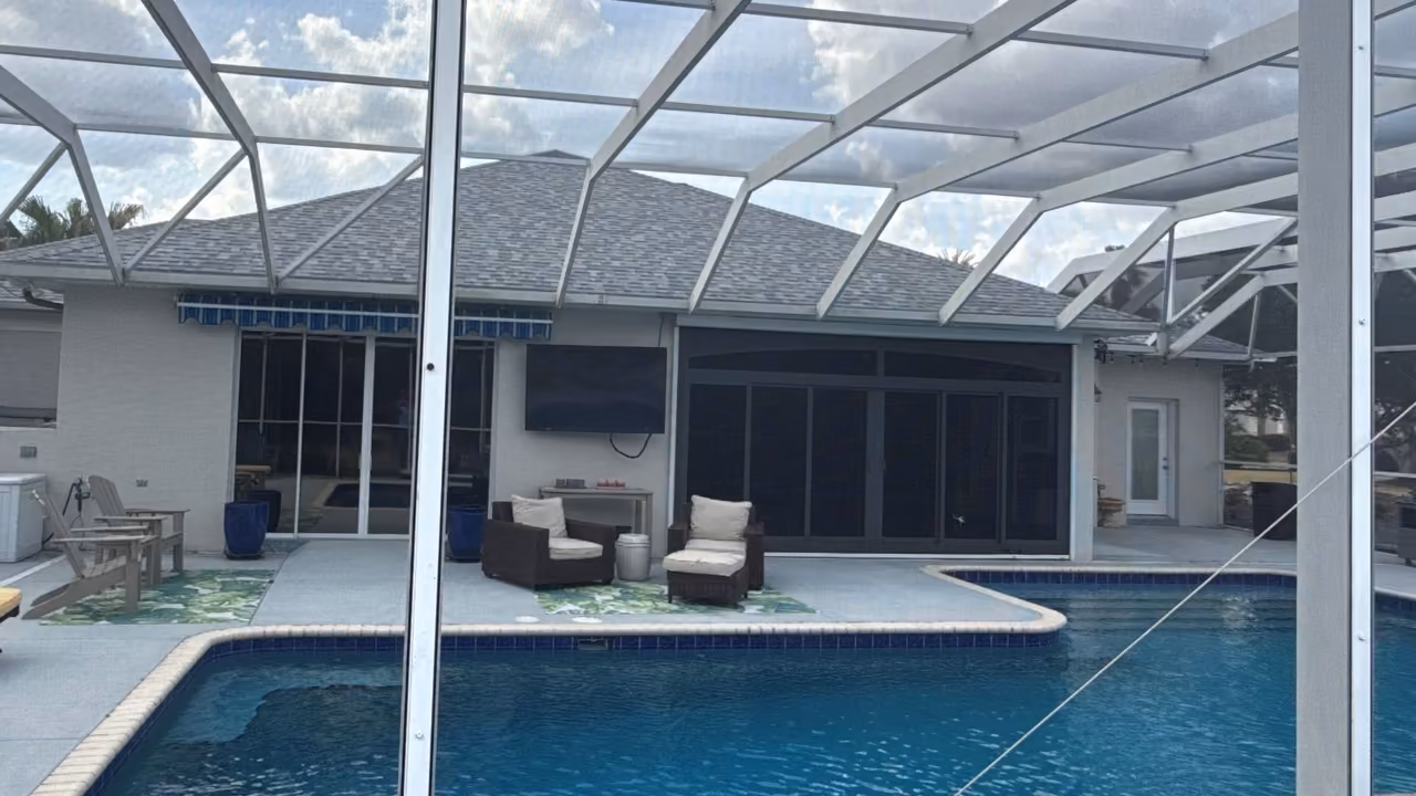Before: screened pool with a painted concrete deck, brick coping and dark tile, ahead of a pool remodel in Florida