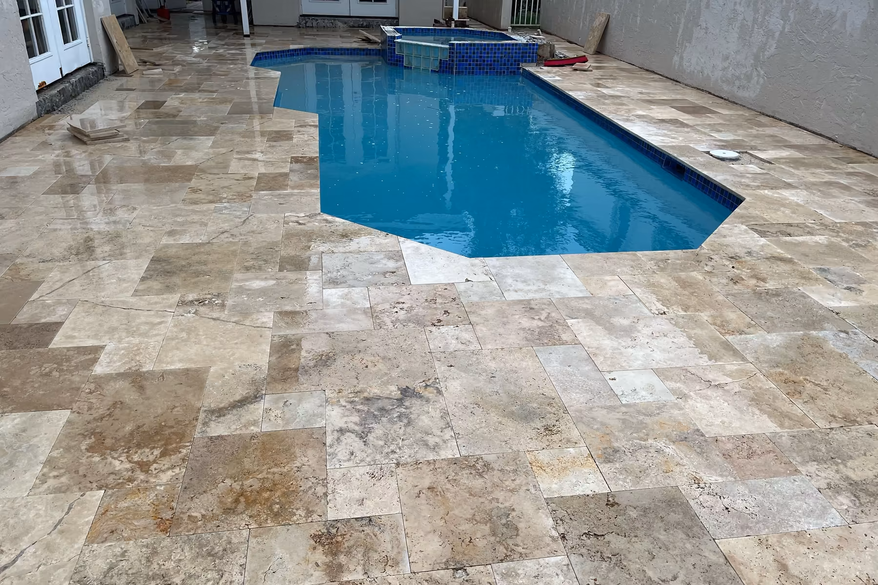 French-pattern travertine deck and cobalt tile around a raised spa, materials for a pool renovation in Florida