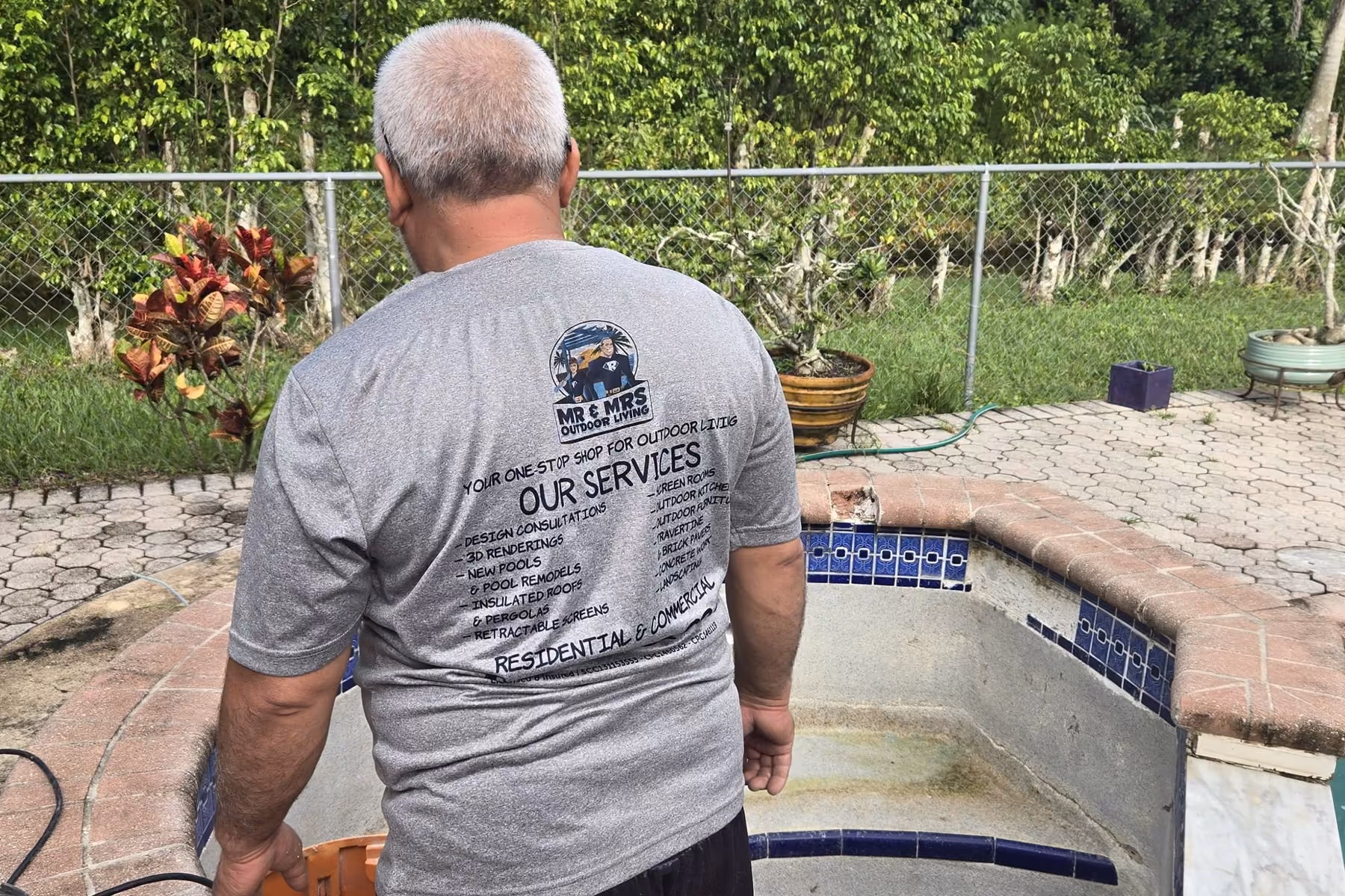 Technician inspecting an old tiled spa with a broken brick coping before a pool remodel in Florida