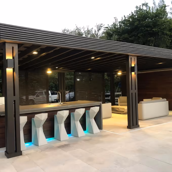 Dark wood pavilion with outdoor bar, sculptural stools, LED toe-kick lights and lounge at dusk.