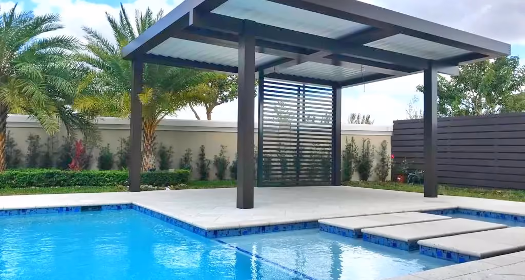 Freestanding dark aluminum patio cover with privacy screen on a pool deck with blue tile pool.