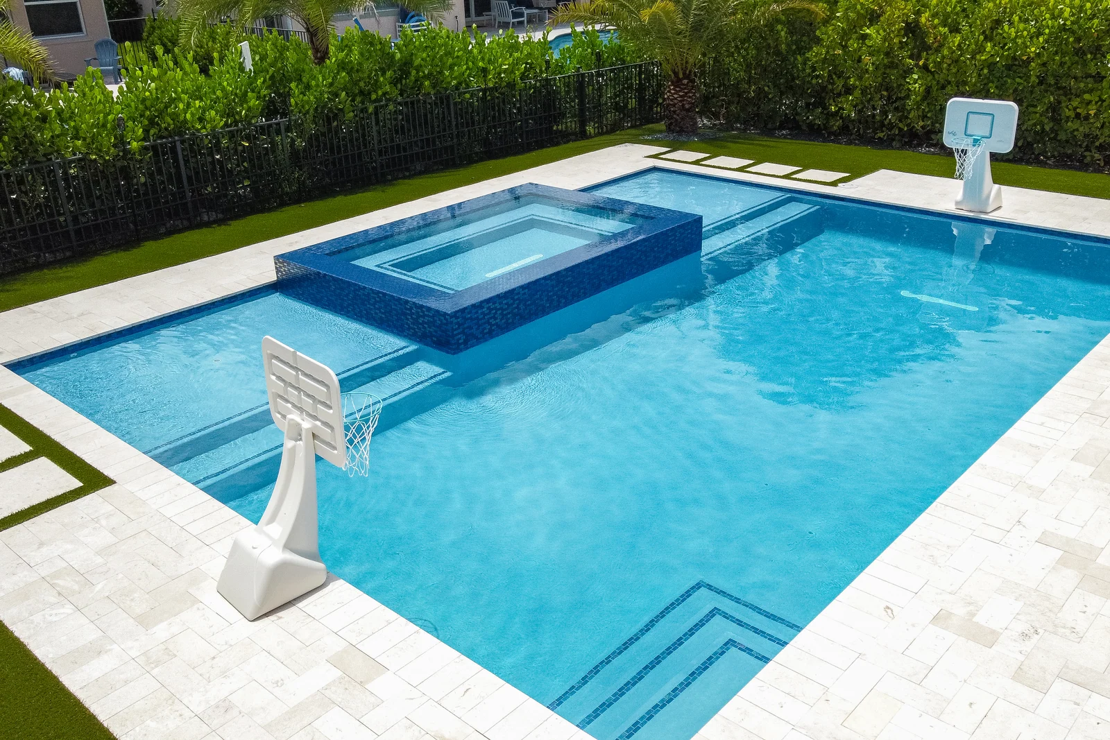 Aerial view of a backyard pool with raised spa and clipped hedge border