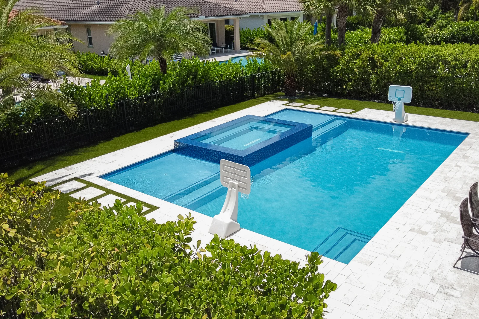Aerial view of a backyard pool with raised spa and travertine-like deck