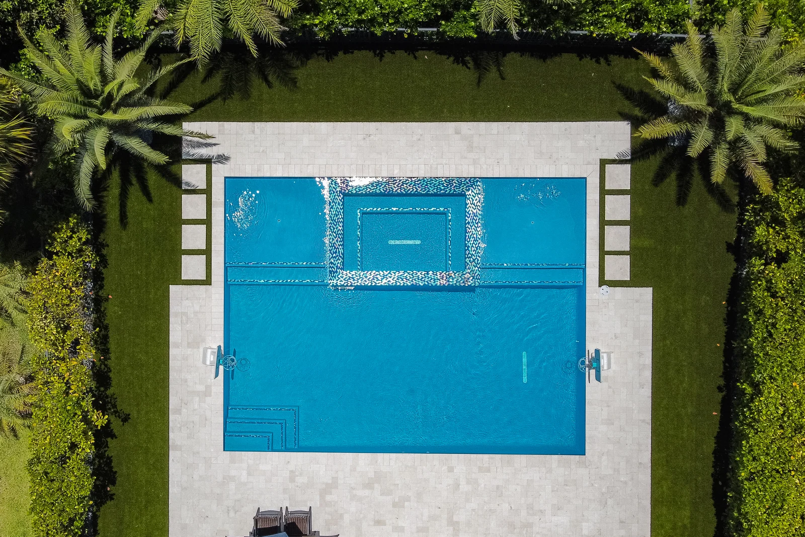 Aerial view of a backyard pool with a sun shelf and raised spa