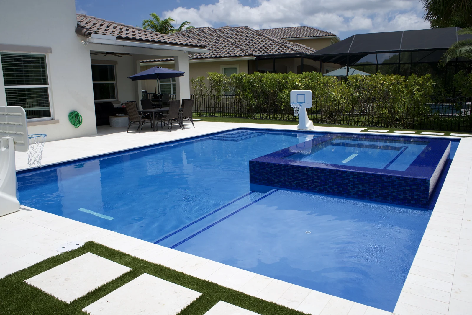 Completed backyard pool with raised spa and artificial-turf deck inlays