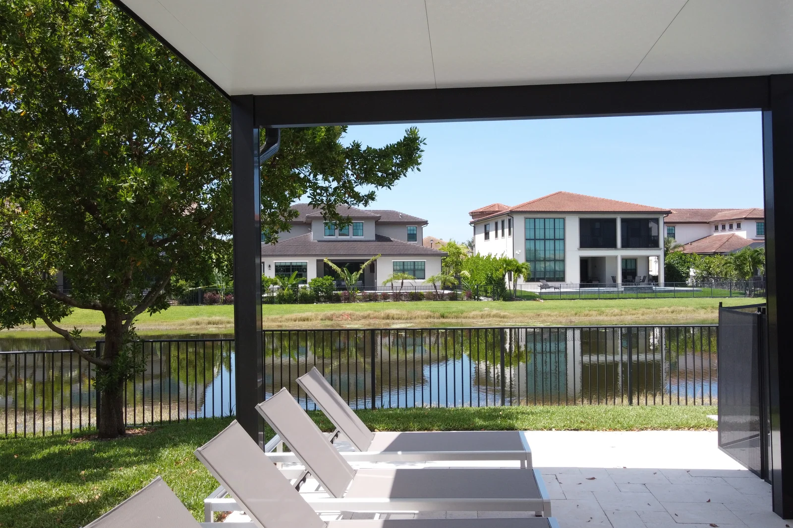 Aerial view of a lakeside backyard with a lap pool and covered lanai