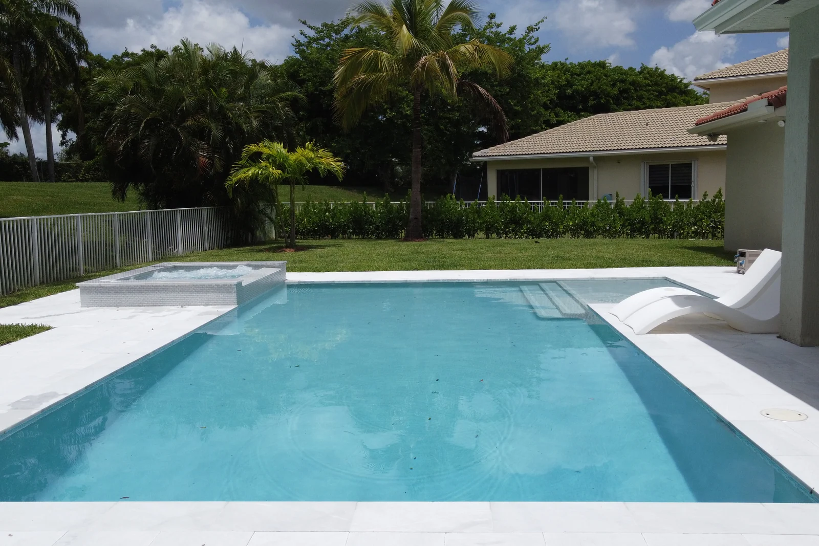 Aerial view of a backyard pool with raised spa and wide stone deck