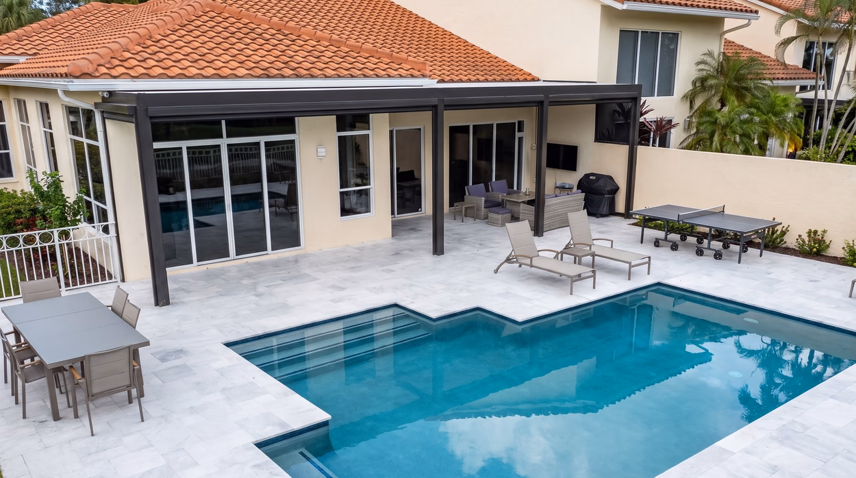 The covered lanai seen along the rear elevation, with the pool steps and the lounge seating.