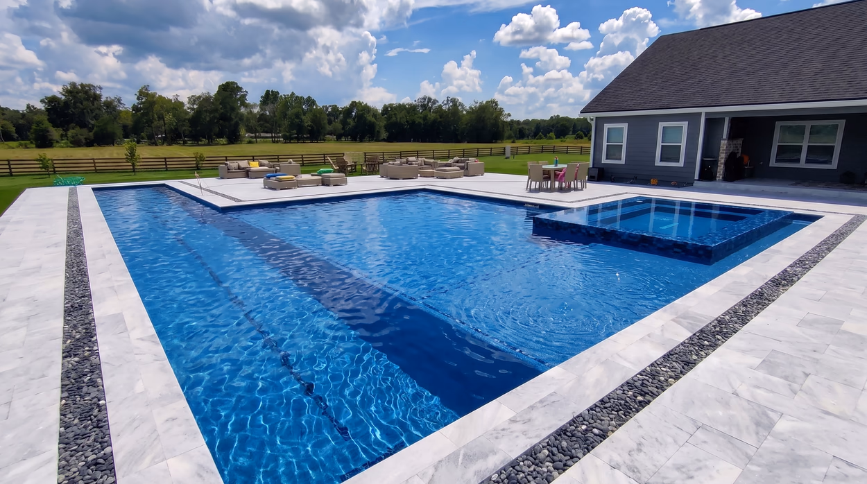 Close view of the pool showing the sun shelf, the tiled waterline and the river-rock border along the deck.