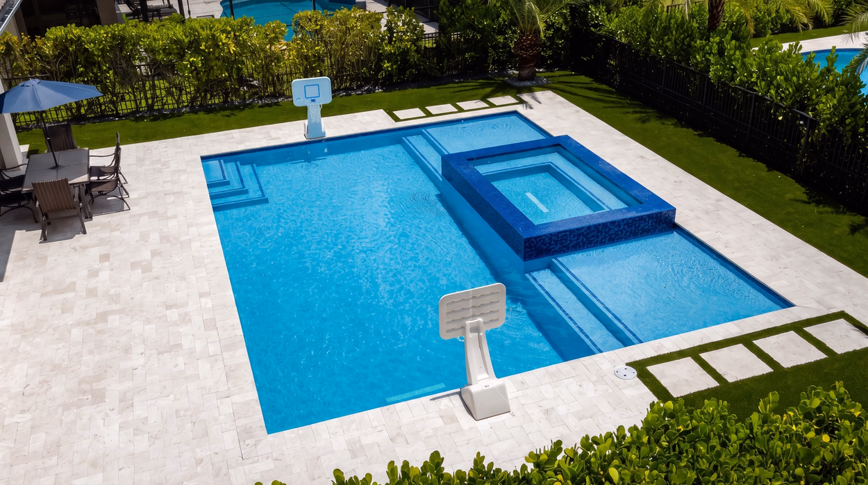 Wide view of the backyard showing the pool, the raised spa and the two poolside basketball hoops.
