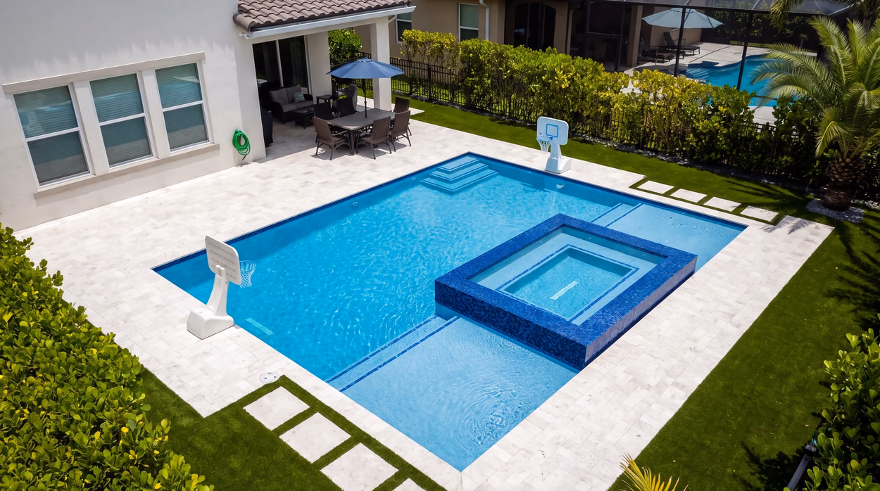Pool and spa from the house side, with the covered patio, dining area and screened neighbouring lanais behind.
