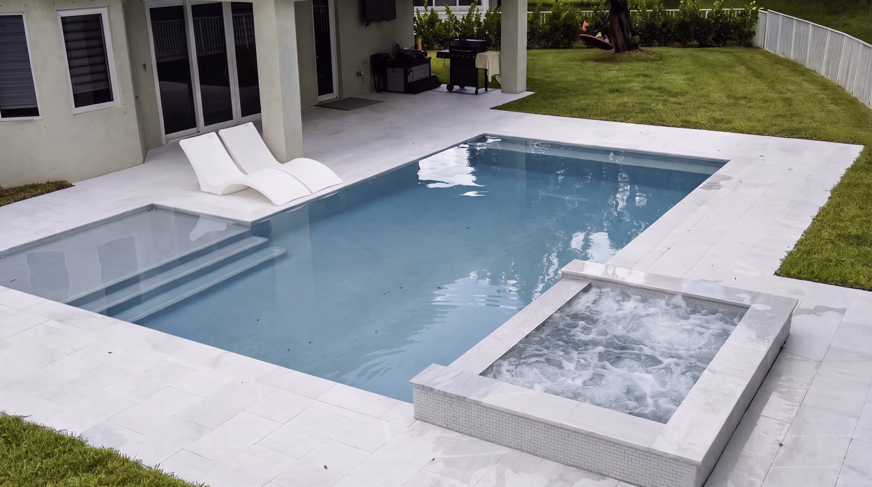 Entry steps and tanning shelf with two white in-pool loungers, beside the bubbling raised spa.