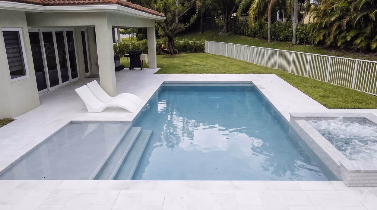 Pool and spa from the lanai, with the sliding glass doors and the marble deck running to the lawn.