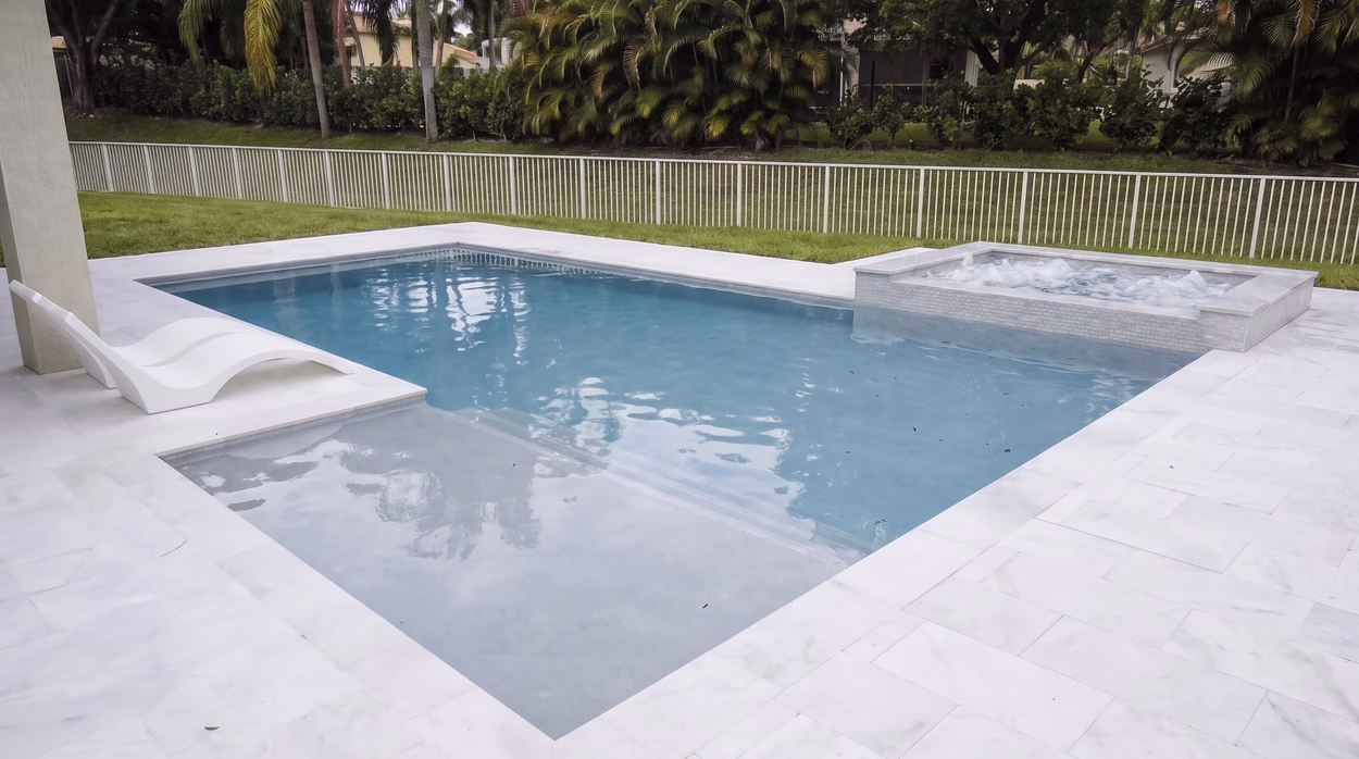 Wide view of the pool, the raised spa and the large-format marble deck pavers.